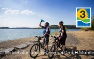 Zwei Radfahrer stehen direkt am Ufer vom Möhnesee