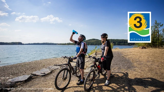 Zwei Radfahrer stehen direkt am Ufer vom Möhnesee